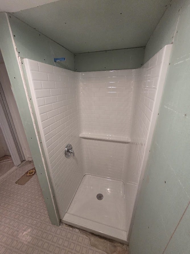New subway-tile shower surround and pan installed in a remodeled bathroom